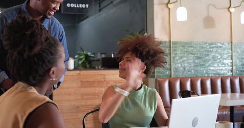 African american friends collaborating in cafe laptop smiling and gesturing casual coworking