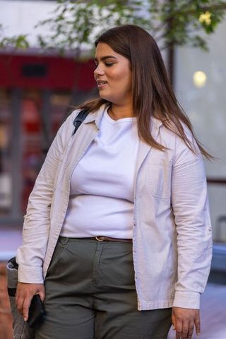 African american woman standing on city street holding smartphone, wearing casual outfit