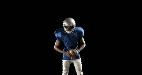Focused American Football Player Holding Ball in Studio with Black Background