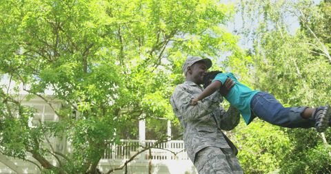 Service Member Joyfully Playing with Son Outdoors