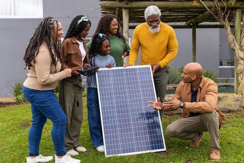 Multigenerational african american family exploring backyard solar panel installation