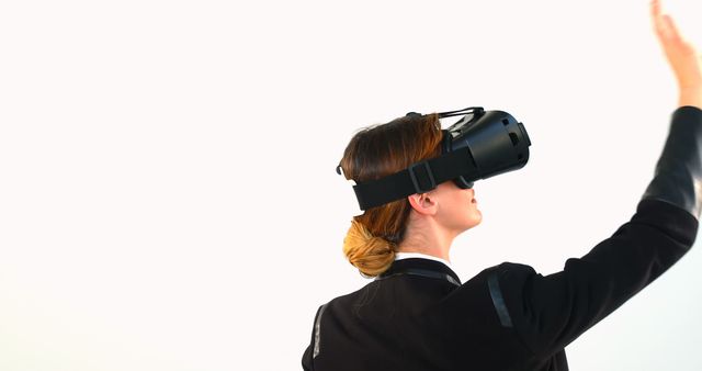 Depicts a woman wearing a virtual reality headset, interacting with virtual environment. Suitable for use in technology articles, VR and gaming industry promotions, innovation showcases, and educational technology content. Perfect for illustrating immersive experiences and futuristic technologies.