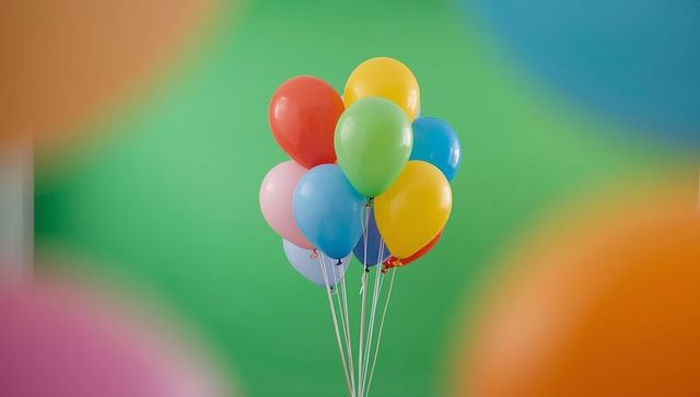 Colorful balloons floating against green backdrop