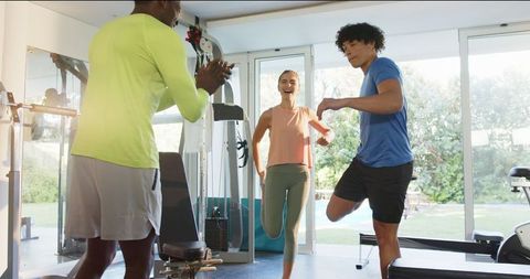 Enthusiastic Couple Exercising with Trainer in Modern Home Gym Setup