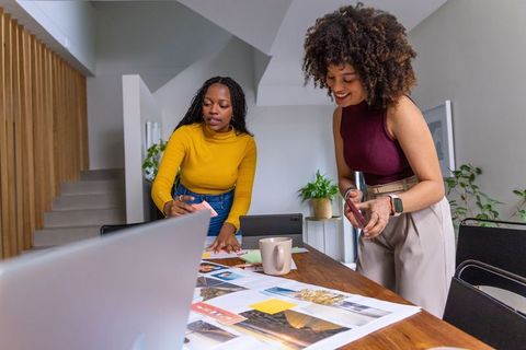African american women collaborating on moodboard and color swatches in modern workspace