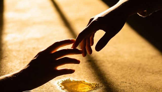 Sunlit fingers reaching: intimate fingertip connection with warm rimlight and golden puddle