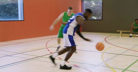 Indoor basketball players dribbling and defending during fast-paced pickup game