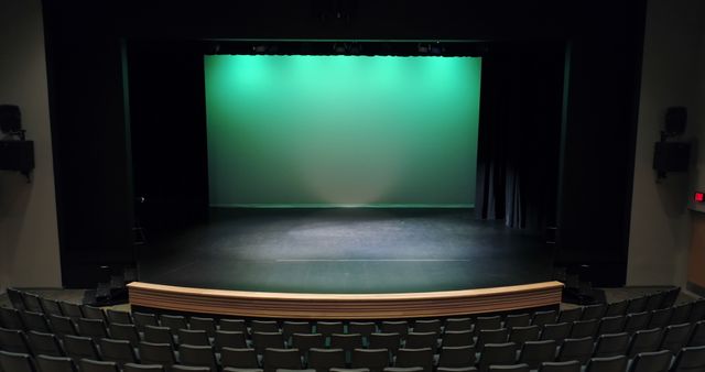 Theatre with green screen, curtain up, stage and empty seats. Theatre, arts and entertainment concept.
