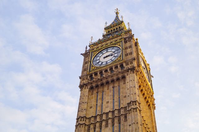 The image captures a close-up view of Big Ben in London during sunset, highlighting the intricate architectural details of the clock tower. The sky takes on a soft, golden hue, adding warmth to the landmark's stone exterior. This image is perfect for use in travel blogs, historical articles, and promotional material for tourism in London. It can also be used in educational contexts to illustrate Victorian architecture and cultural heritage.