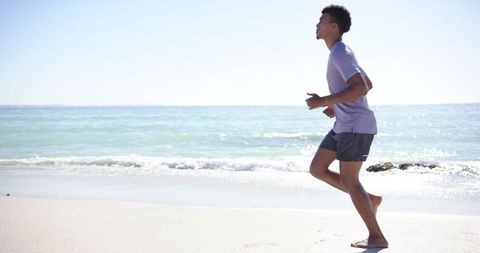 Young Athletic Man Jogging by Ocean Shoreline