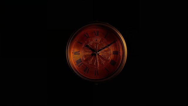 Vintage wooden clock glowing on dark wall