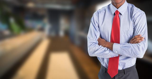 Businessman confidently standing with arms crossed in a modern office environment. Ideal image for use in corporate marketing materials, leadership articles, business presentations, and professional services promotions. Highlights professionalism, success, and executive presence.