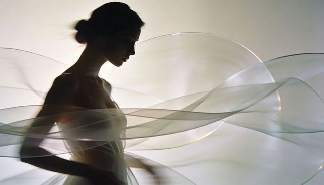 Silhouette fashion model wearing sculptural translucent hoops around strapless gown
