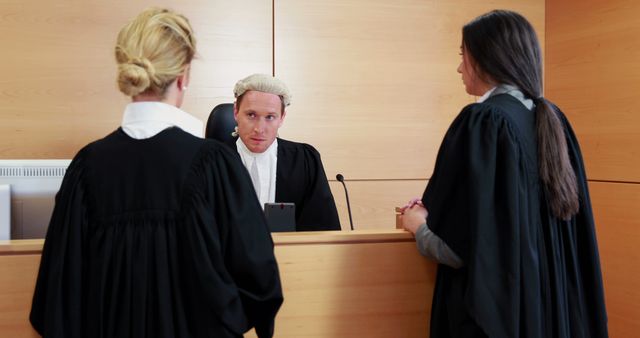 A male judge attentively hears two female lawyers in a serious courtroom setting. - Download Free Stock Photos Pikwizard.com