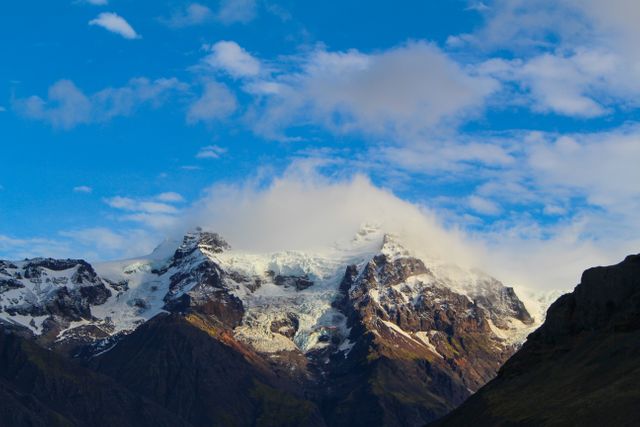 Snow-capped mountain peak against blue sky with clouds - Download Free Stock Photos Pikwizard.com