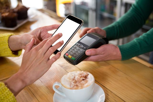Customer using smartphone for contactless payment at a cafe. Ideal for illustrating modern payment methods, digital transactions, and the convenience of cashless payments in everyday life. Suitable for articles on technology, finance, and retail.