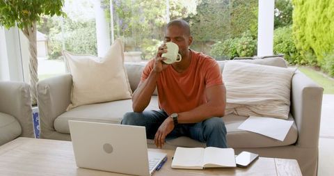 Man Relaxing with Coffee and Laptop in Cozy Living Room