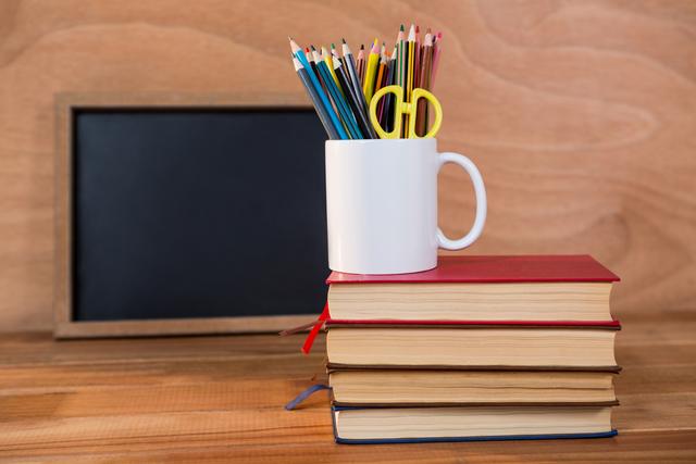 Close-up of books stack with colored pencil on a mug