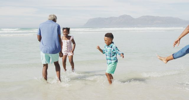 Happy african american couple playing with children on sunny beach. healthy and active time beach holiday.
