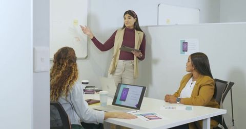 Indian businesswoman presenting app mockups to team during collaborative office meeting