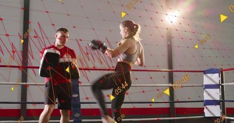Female boxer training with coach in AR-enhanced boxing ring delivering dynamic kick