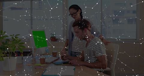 Collaborating team using tablet with digital network overlay in bright modern coworking workspace