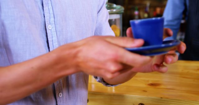 Caucasian man holding blue cup on plate in cafe, copy space - Download Free Stock Photos Pikwizard.com