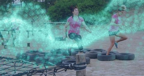 Women conquering tire obstacle course outdoor fitness concept