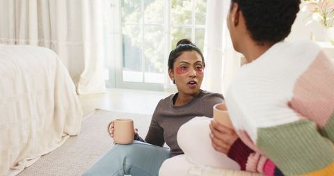 Diverse Female Friends Relaxing with Under-Eye Patches in Cozy Bedroom