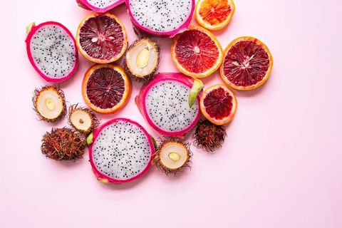 Sliced dragon fruit and fresh exotic fruits mix on pink background