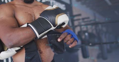 Adjusting boxing hand wraps and glove shirtless boxer preparing for training