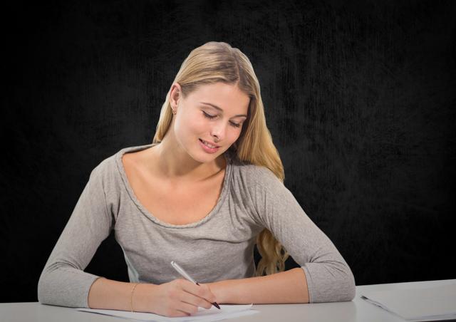 Beautiful woman writing on a piece of paper against black background
