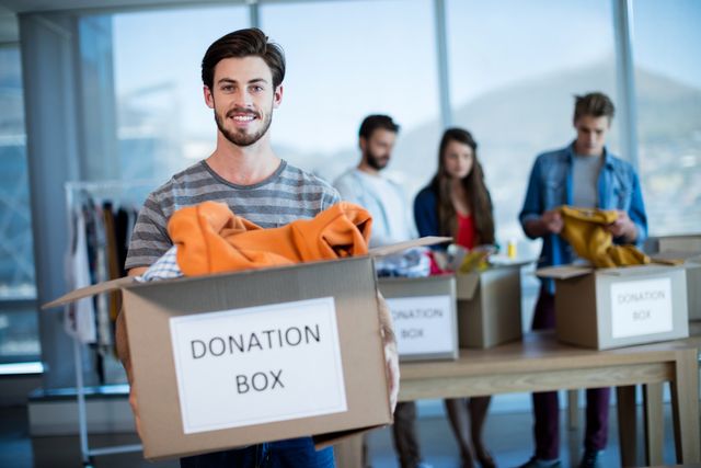 Portrait of smiling man holding a donation box in office