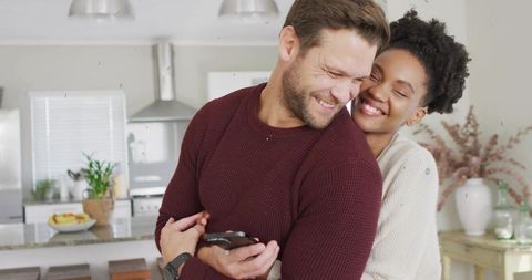 Romantic Couple Embracing in Modern Kitchen with Smartphone
