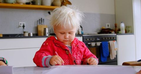 Blond Toddler Engaged in Drawing at Modern Kitchen Table