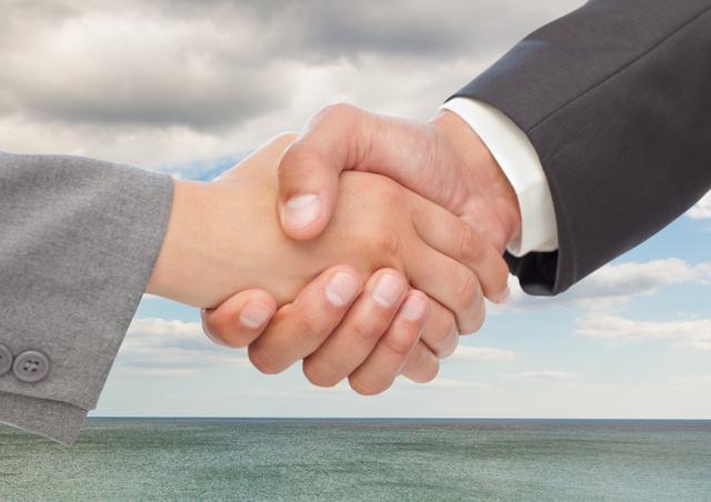 Digital composite image of businesspeople shaking hands against sea and clouds
