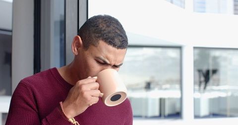 Mid Adult Man Relaxing with Coffee in Modern Office Lounge