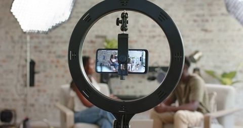 African american co-hosts recording casual interview using smartphone mounted in ring light
