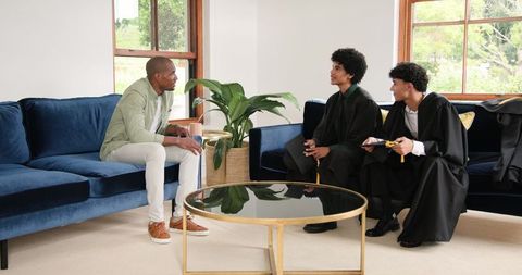 Proud Father with Sons in Graduation Caps and Gowns at Home