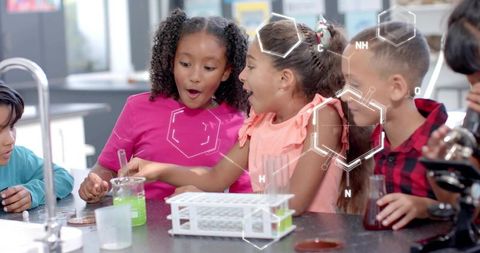 Elementary students conducting colorful chemistry experiment with green liquid and dropper