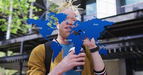 Young man using smartphone holding coffee cup with world map overlay in urban plaza