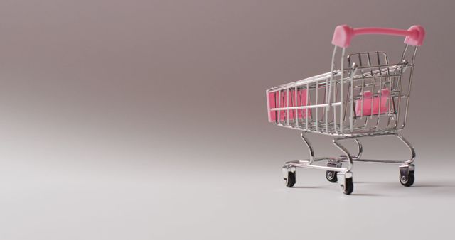 Shiny empty shopping cart with pink handle placed on gradient grey background. Perfect for illustrating concepts related to retail, online shopping, consumer behavior, commerce, and sales promotions. Suitable for use in advertisements, marketing materials, blog posts, and websites focused on shopping and retail.