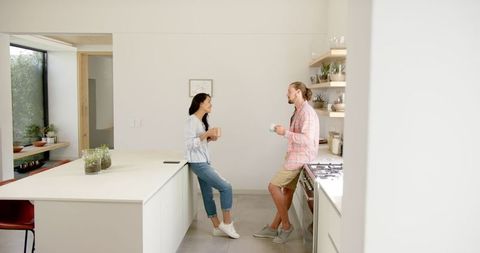 Young Couple Conversing in Modern Kitchen with Coffee