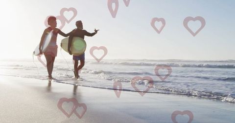 Couple Walking Beach with Surfboards at Sunrise