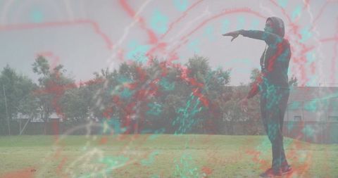 Pointing man wearing hooded jacket on grassy field with teal abstract overlay, copy space