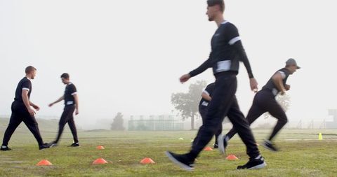 Male athletes engaging in teamwork training on foggy field