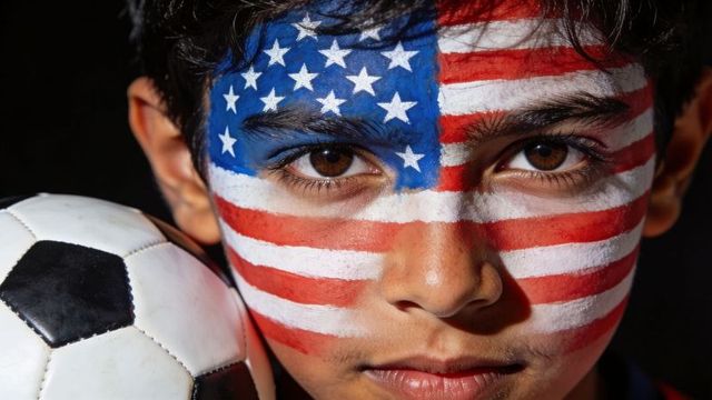 Young soccer fan wearing us flag face paint holding ball closeup patriotic portrait