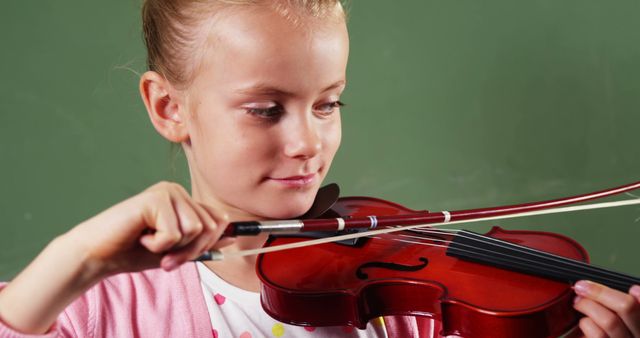 Young girl deeply concentrating while practicing violin. Ideal for use in educational materials, promoting music schools or programs, illustrating childhood activities, or for ads related to music instruction and talent development in children.