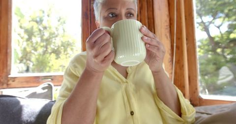 Senior Woman Relaxing with Tea on Cozy Sofa in Bright Home