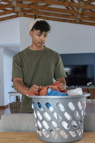 African american man sorting laundry in rustic living room with natural light